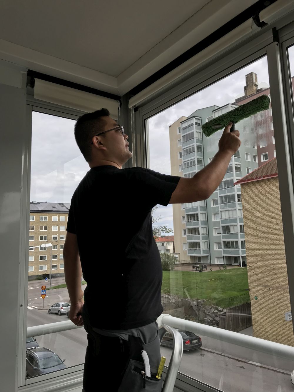 Fönsteputs kille tvättar fönster med skrapa